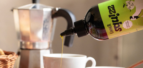 Aceite Squizz sirviéndose desde su dosificador junto a una cafetera